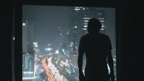 Man-Opening-Curtains-of-City-Window-at-Night