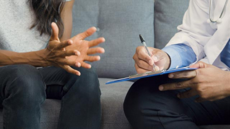 Doctor-Writing-On-Clipboard-with-Patient